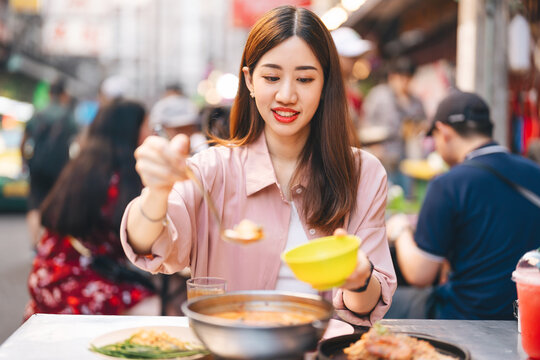 Young adult traveler woman enjoy eating street food spicy thai tasty menu travel at chinatown Yaowarat, Bangkok, Thailand