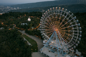 Drone aerial photo of colorful illuminated Ferris wheel with Mtatsminda Park attraction grounds in background during dark night twilight in Tbilisi © yuriyzhuravov