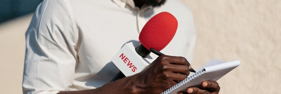 News reporter writing in notebook beside red microphone for interview banner and media background for press reporting and live coverage