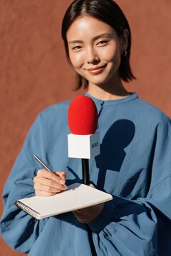 Female reporter with red microphone and notebook for interview background and journalism banner design for media coverage and press stories