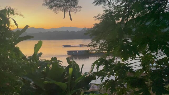 Video Shot of the Mekong River at sunset with two traditional boats passing by in Luang Prabang, Laos