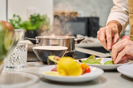 Person preparing healthy meal cutting avocado in kitchen