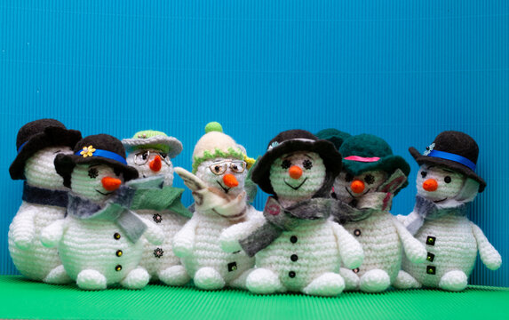Snowmen crocheted from yarn, set against a colorful background