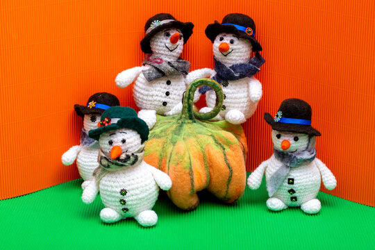 Snowmen crocheted from yarn, set against a colorful background