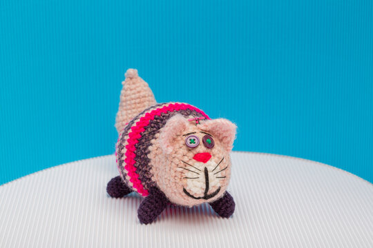 Cat crocheted from yarn against a colorful background
