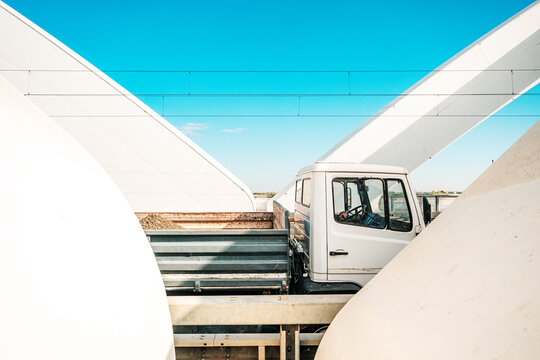 Light cargo truck passing through a contemporary white arch bridge, concept of transport, logistics and delivery, with copy space in a bright sky