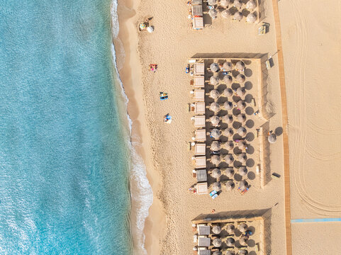 Aerial top view of a beach in Greece with sunbed and sunshade at summer day