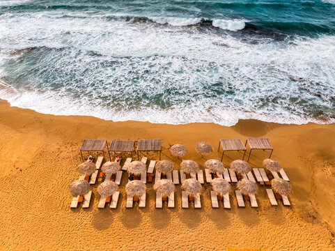 Aerial top view of a beach in Greece with sunbed and sunshade at sunset