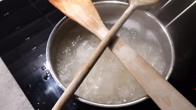 Stockholm, Sweden Rice boils in a pot of water as two wooden spoons prevent the water from boiling over. 