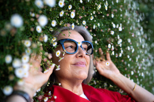 White woman with glasses lying among daisies outdoors
