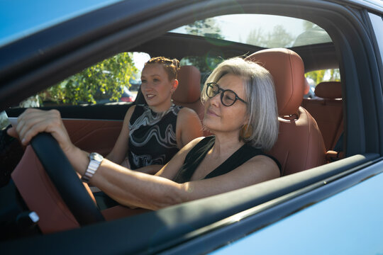 White woman driving car with passenger on sunny day
