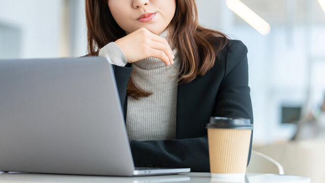 パソコンを使いながら考えごとをする女性・ビジネスウーマン, Businesswoman Thinking While Using a Laptop