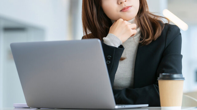 パソコンを使いながら考えごとをする女性・ビジネスウーマン, Businesswoman Thinking While Using a Laptop
