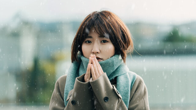 雪が降る街角に立つ女性