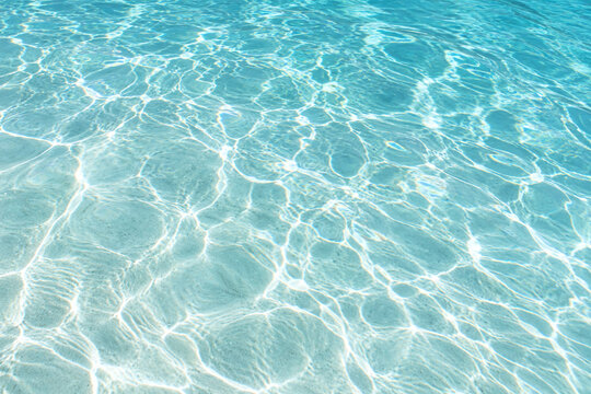 Sunlit water caustics on a pale pool floor