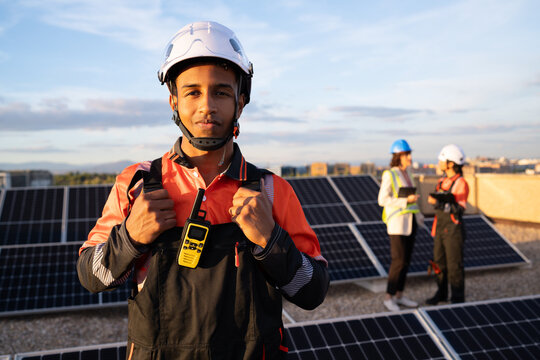 Hispanic and white worker with walkie talkie on rooftop solar panel