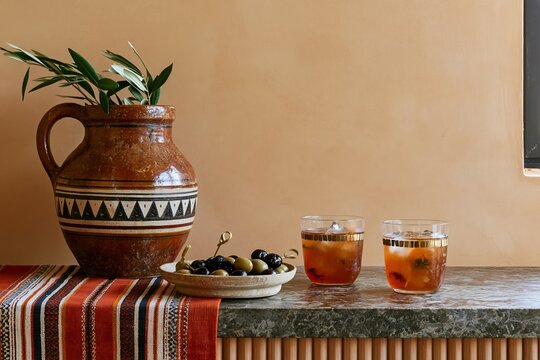 Afrobohemian table setting with ceramic jug, olives, amber drinks, and striped textile