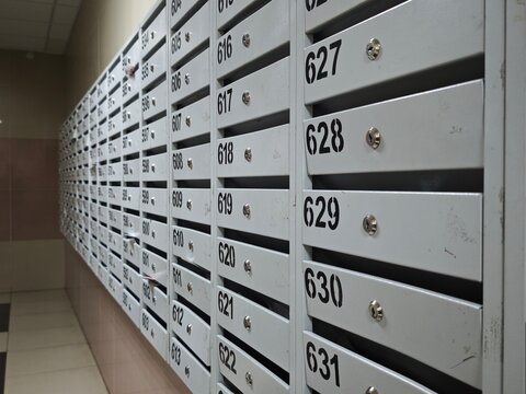 Rows of numbered metal mailboxes in a modern apartment building entrance, residential correspondence and secure personal mail storage