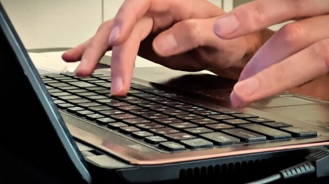Extreme close-up of male hands actively typing on a black laptop keyboard, ideal for business promos, remote work software ads, and technology tutorials.