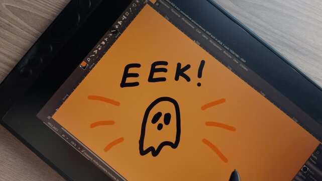 Digital illustration takes shape as hand uses stylus to decorate startled cartoon ghost with orange lines. Tablet drawing features bold black outlines and playful Halloween style. Halloween