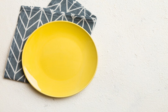 Top view on colored background empty round yellow plate on tablecloth for food. Empty dish on napkin with space for your design