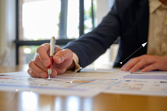 Businessman using pen analysing data charts on table in modern office in Business planning and investment financial data analytics graph Financial management technology concept.