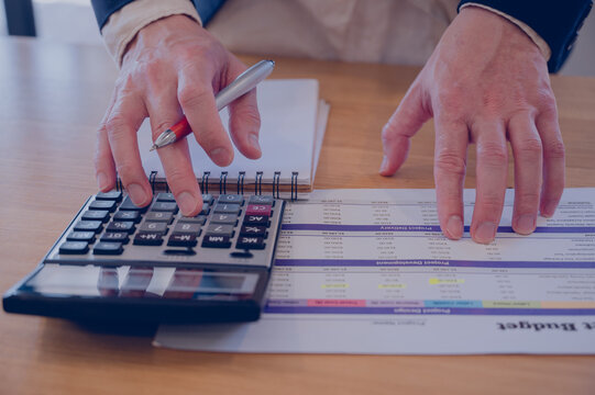 Businessman using calculator and working with business financial report, accountant using calculator calculate while working analytic business report, Planning financial and accounting concept.