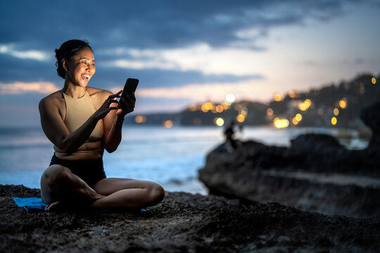Asian digital nomad and freelancer woman creating content on smartphone at sunset