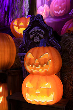 Spooky Halloween decorations with glowing Jack O Lantern pumpkins and a creepy tombstone