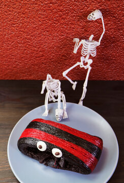 Spooky chocolate pastry decorated with mini skeleton toys for a Halloween theme snack