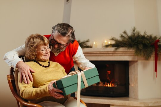 Senior couple sharing christmas gift during holiday celebration