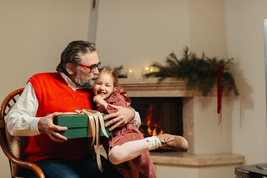 Grandfather kissing happy granddaughter receiving christmas present