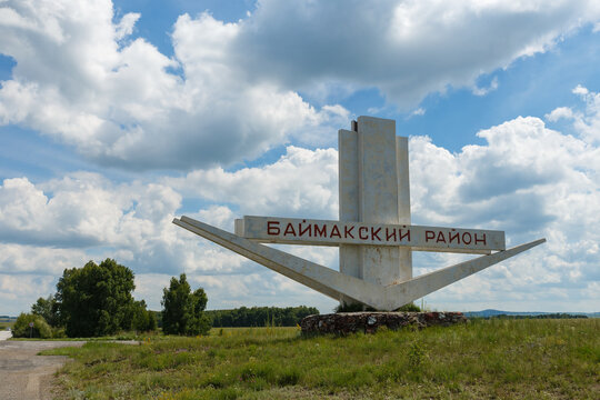 Bashkortostan, Russia - June 26, 2026: White concrete entrance stele of Baymaksky District on roadside in Bashkortostan Russia under blue sky with fluffy white clouds