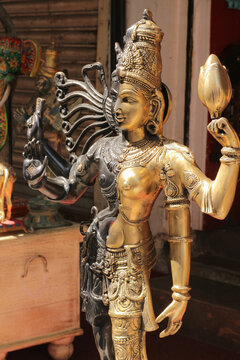 A vertical close up of a dual metal Ardhanarishvara statue on a vintage wooden chest.
