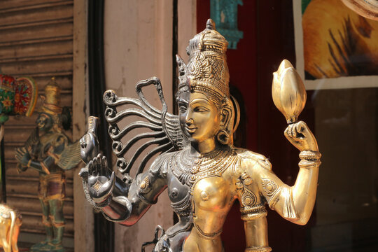 A horizontal close up of a dual metal Ardhanarishvara statue at an outdoor street bazaar.