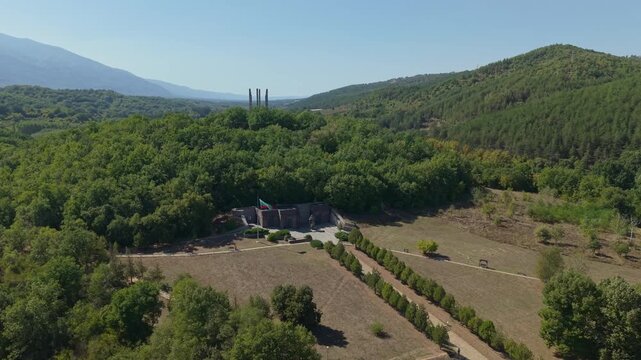 Aerial drone footage showcases the iconic Tsar Samuil Monument with the Bulgarian flag waving against the backdrop of mountains and the historic landscape of southwestern Bulgaria.