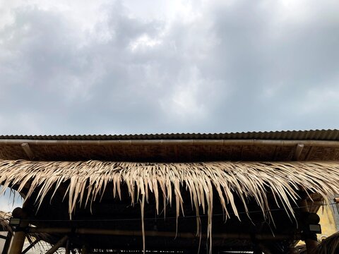 thatch roof eaves on bamboo hut against cloudy sky