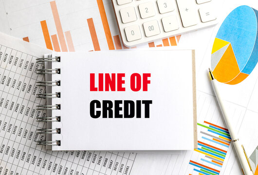 Line of credit text on a notebook with calculator, charts and pen, banking finance and loan borrowing concept