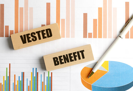 Vested benefit text on wooden blocks with charts and pen, finance concept illustrating pension entitlement and retirement planning