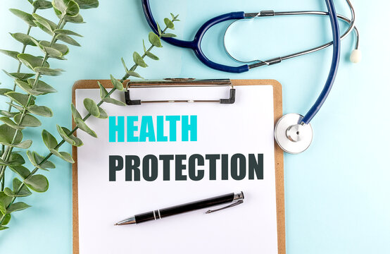 Health protection text on a medical clipboard with stethoscope, pen and green leaves on a blue background, healthcare