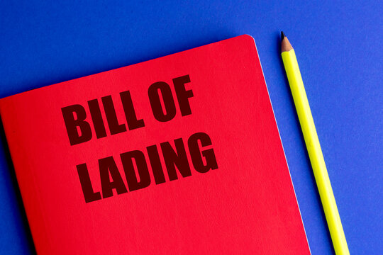 Bill of lading text on a red notebook beside a yellow pencil against blue background