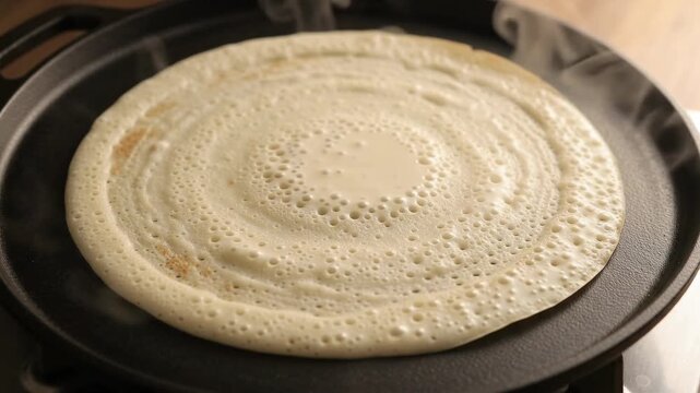 Crepe batter bubbling and cooking on hot cast iron griddle