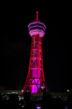 Hakata Port Tower glows red and magenta over the waterfront in Fukuoka after dark