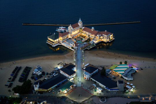 Aerial view of an illuminated waterfront complex and sandy beach at dusk in Fukuoka, Japan