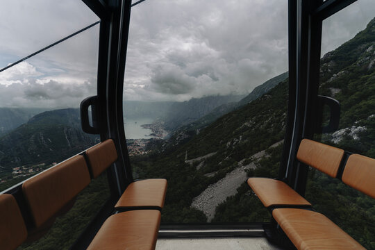 POV view from empty cable car cabin looking at mountains and valley under dramatic sky