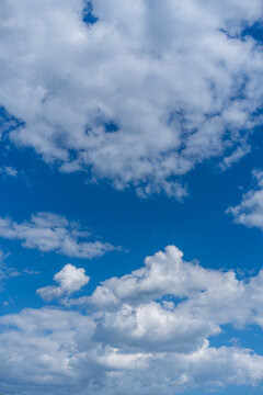 Vertical view of beautiful blue sky with fluffy white clouds on a sunny day