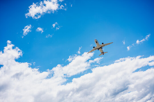 Airplane flying in the beautiful blue sky with fluffy white clouds