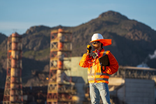 Industrial worker in safety gear, communicating by radio at a mountain plant