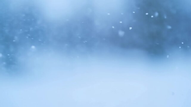 Intentionally blurred blue snow particles drift through a soft atmospheric haze. Winter title cards, seasonal promotions, and weather programming.