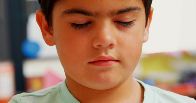 Front view of blind Caucasian schoolboy reading a braille book at desk in classroom at school